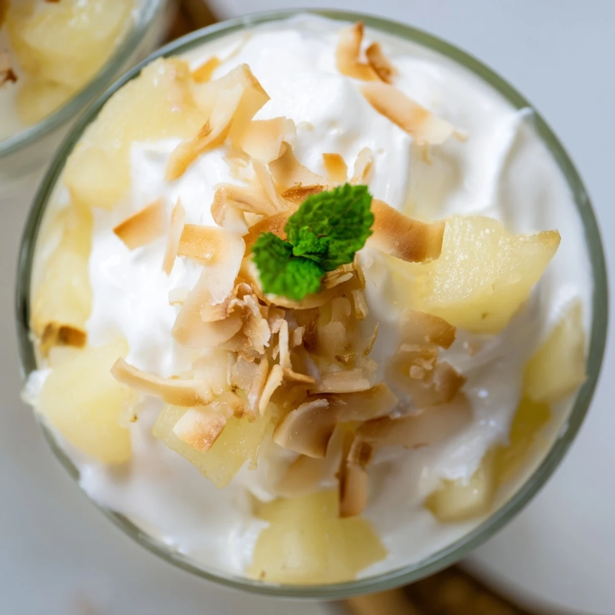 Mini pineapple condensed coconut milk topped with golden coconut flakes and bright green mint leaves