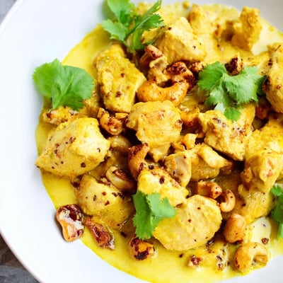 Tender chicken pieces simmer in a spiced coconut curry sauce with cashews alongside aromatic saffron rice.