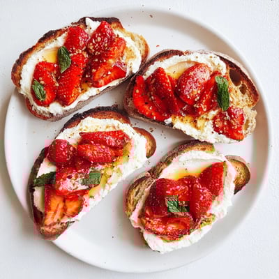 Roasted Strawberry Whipped Ricotta Toast arranged on a rustic plate with fresh mint and black pepper garnish.