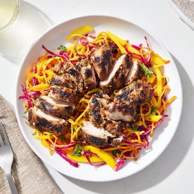 Grilled spicy jerk chicken with sweet mango slaw on a summer plate