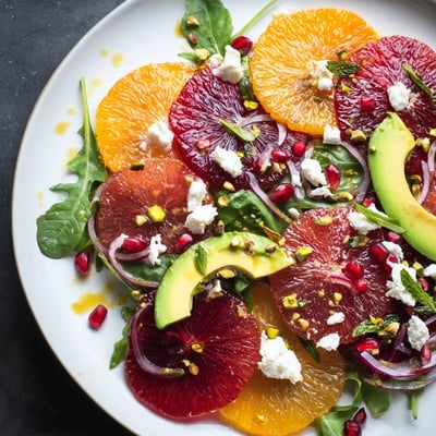 Vibrant citrus salad with pomegranate jewels, sliced avocado, and tangy feta over fresh greens